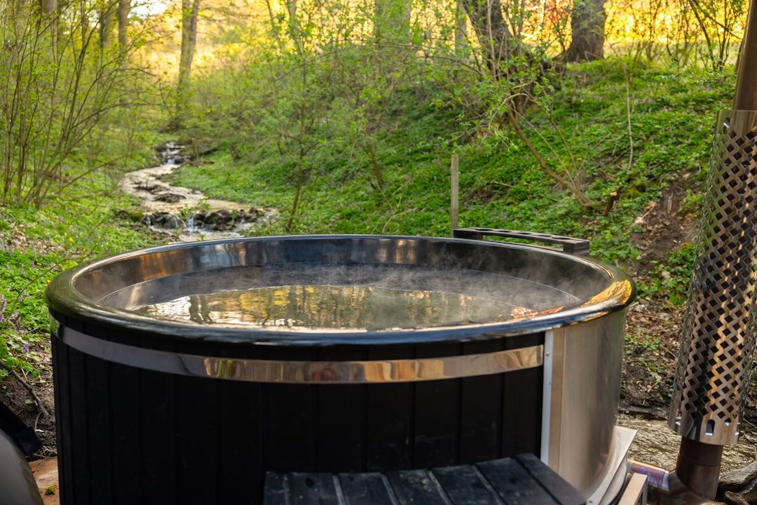 A serene camping scene with a hot tub in a forest clearing.